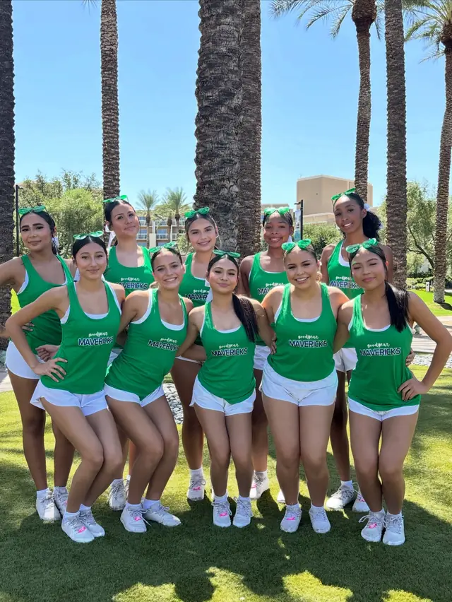 The squad in green camp shirts and bows under the palm trees at UCA camp