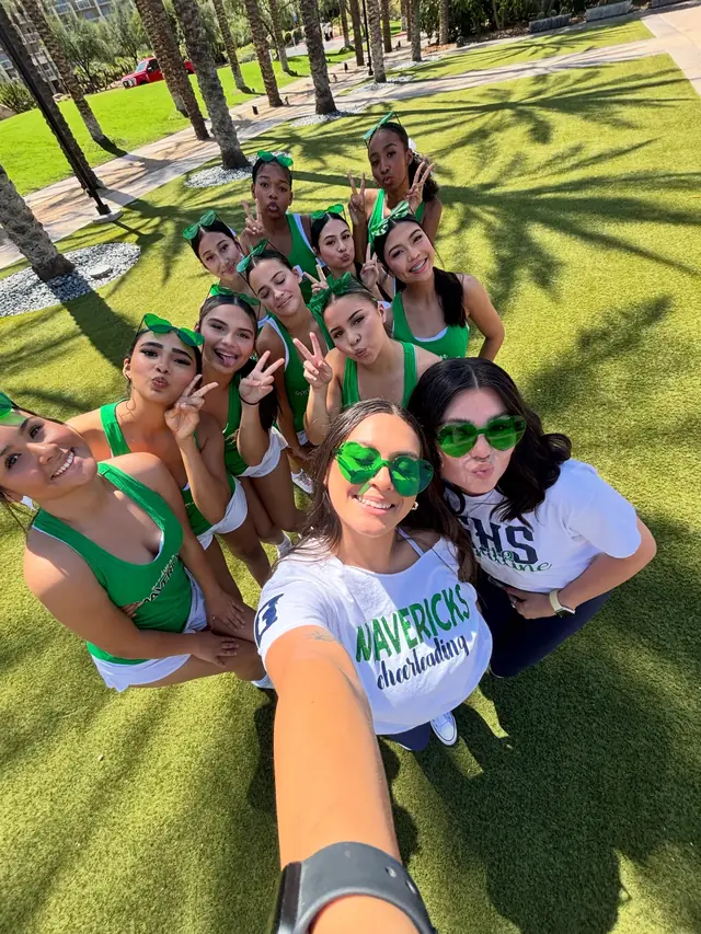 A camp selfie of the squad in green shirts and sunglasses on the lawn