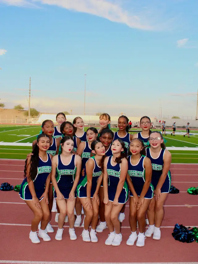 The 2026–27 Goodyear cheer team together on the track at sunset, poms at their feet